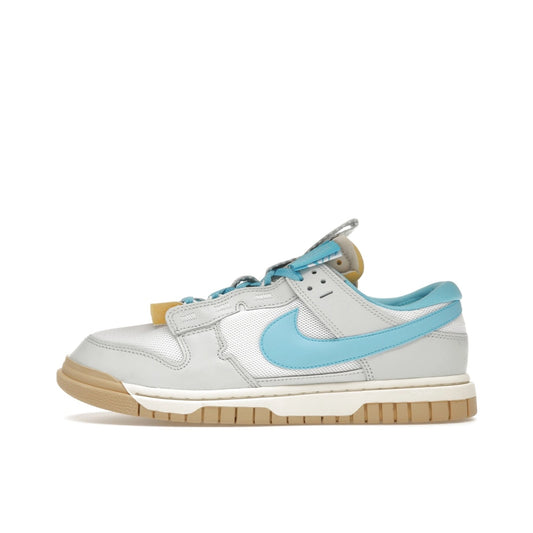 Nike Dunk Low Jumbo Photon Dust, side view, with oversized Baltic Blue Swoosh and grey upper.