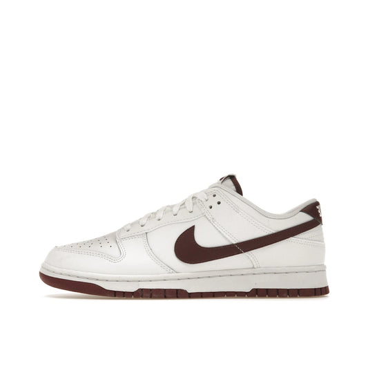 Nike Dunk Low Retro sneakers, side view, in white with night maroon overlays.