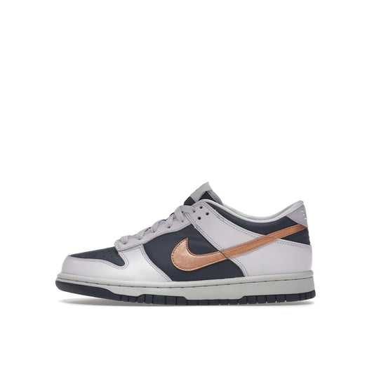 Nike Dunk Low SE GS sneakers, side view, in navy blue with metallic copper swoosh.