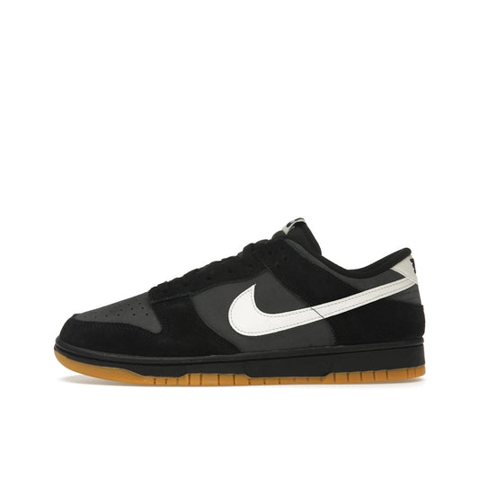 Nike Dunk Low SE, side view, in black and grey leather with gum sole.