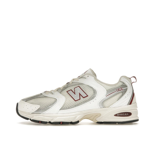 New Balance 530 sneakers, side view, in sea salt with mercury red accents.