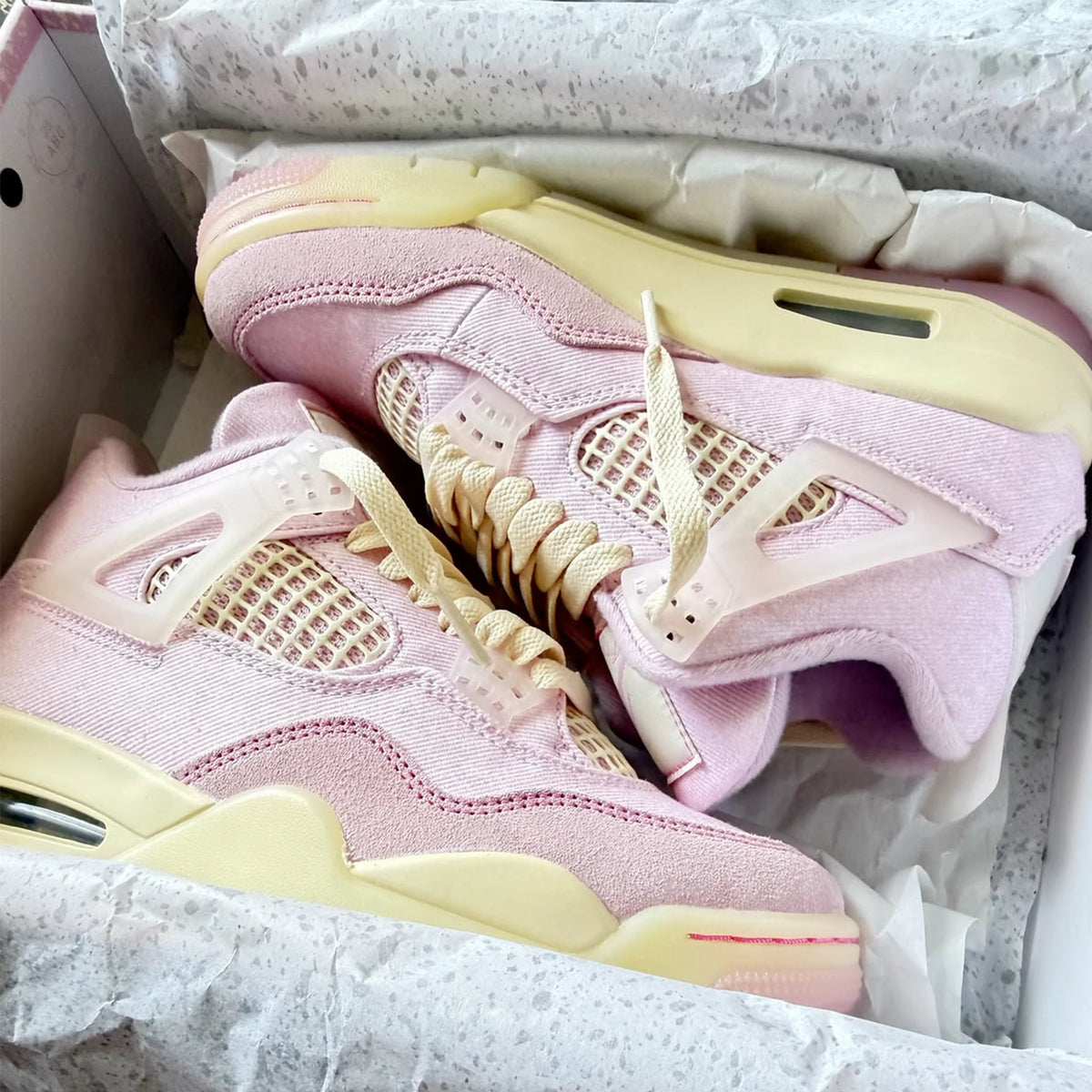 Pink Air Jordan 4 sneakers with cream accents in a shoebox