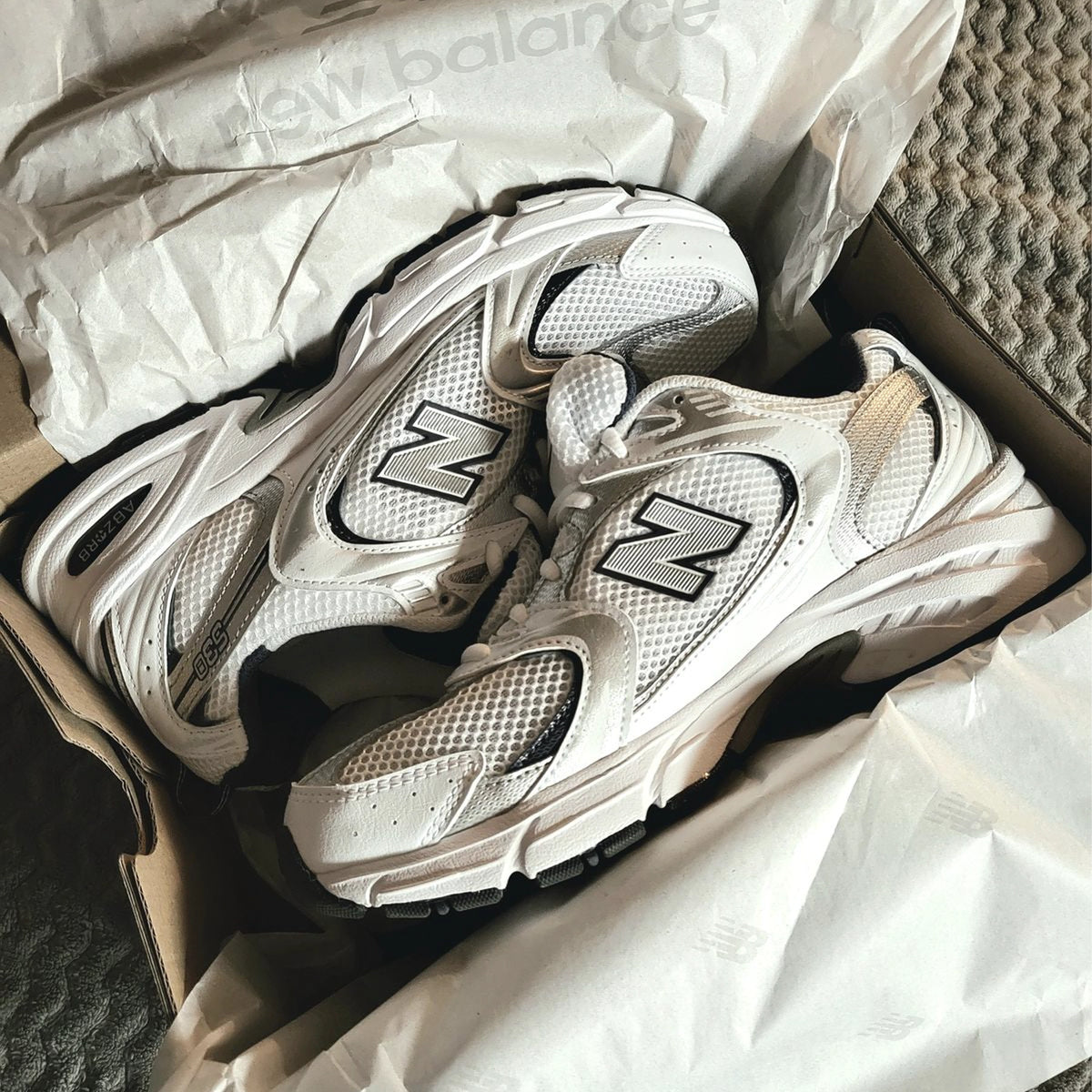 White and grey New Balance 530 sneakers in a shoebox